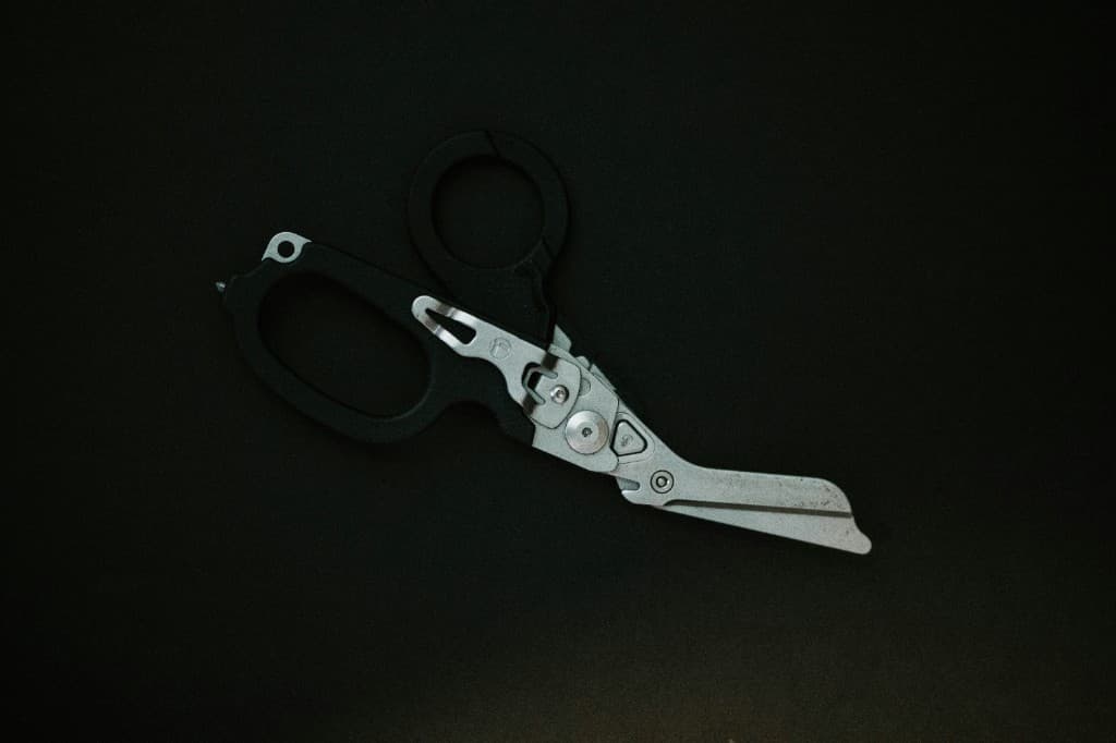 Rescue trauma shears photographed on a dark surface.